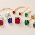Composition élégante de bijoux en or sertis de diamants, rubis, saphirs et émeraudes, disposés sur un fond clair.
