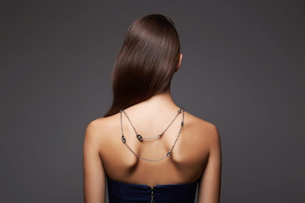 Femme portant un collier de dos avec une robe élégante au dos nu.